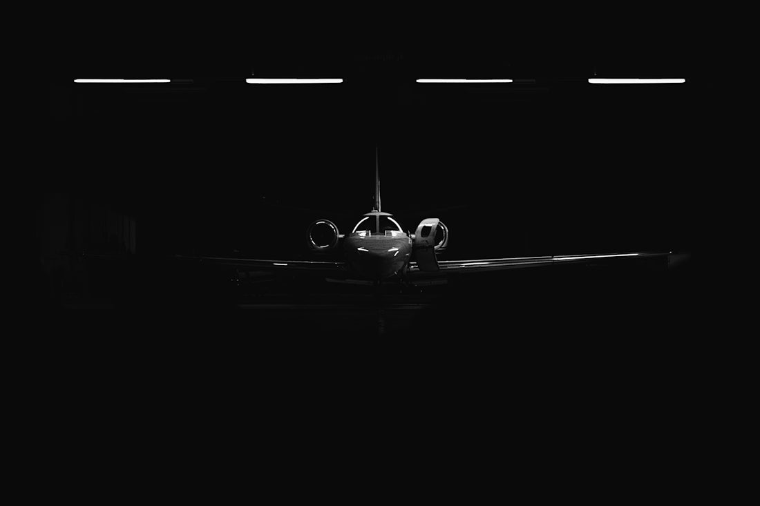 silhouetted private jet in dark hangar