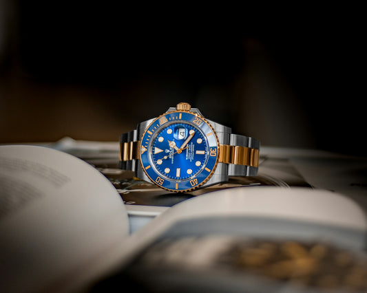 A blue and gold luxury wristwatch resting on an open book